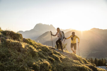 Wanderer:innen genießen die besondere Stimmung und das warme Licht in der Bergwelt rund um St. Johann in Tirol.
